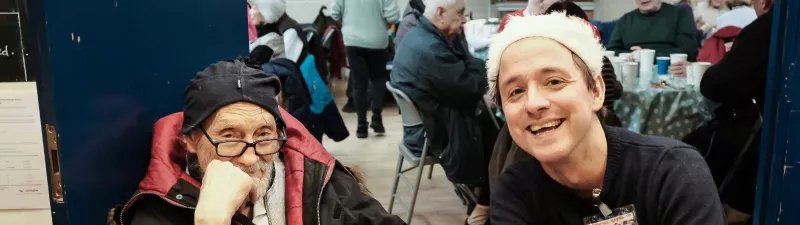 A volunteer with an older man at Christmas lunch