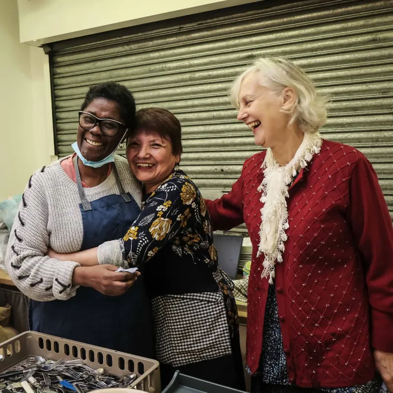Three Community Lunch volunteers laughing in the kitchen