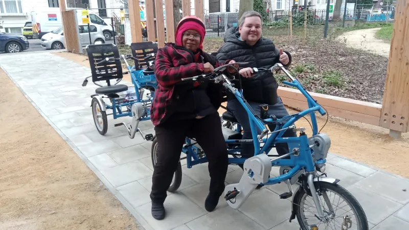 A volunteer and Abbey member riding a mobility bike into Abbey Community Centre